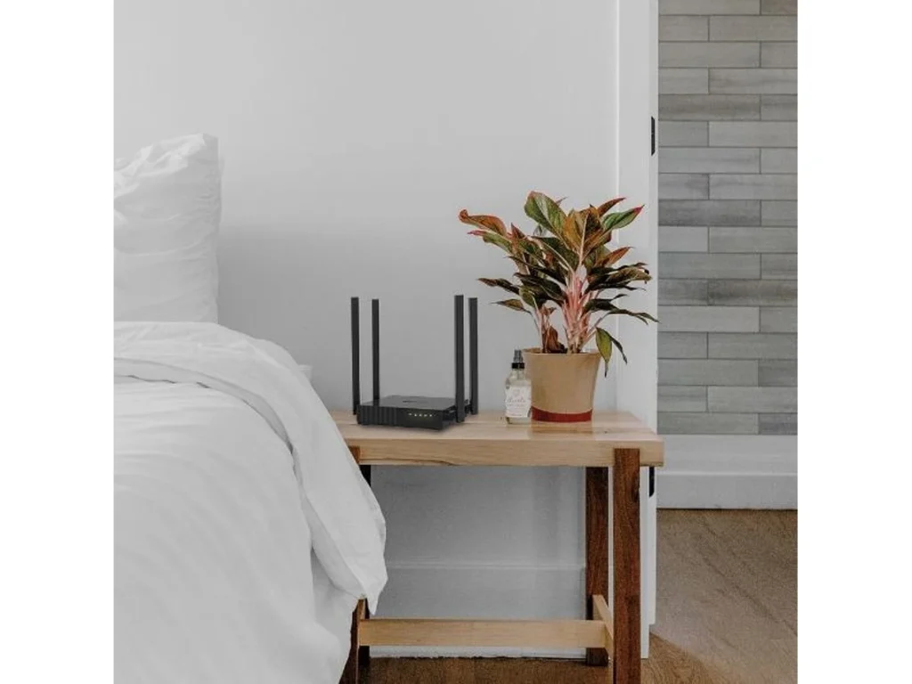 Mesa de cabeceira com planta e router Wi-Fi.