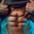 Homem a mostrar abdominais definidos sob iluminação dramática azul.