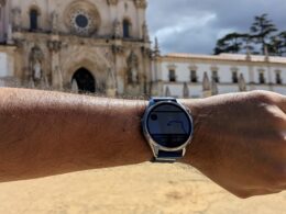 Huawei Watch GT 7 num pulso com o Mosteiro de Alcobaça ao fundo.