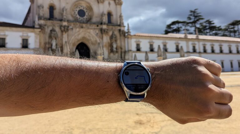 Huawei Watch GT 7 num pulso com o Mosteiro de Alcobaça ao fundo.