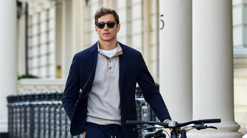 Homem elegante com blazer azul e bicicleta em ambiente urbano.