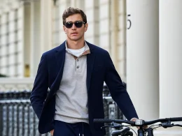 Homem elegante com blazer azul e bicicleta em ambiente urbano.