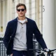 Homem elegante com blazer azul e bicicleta em ambiente urbano.