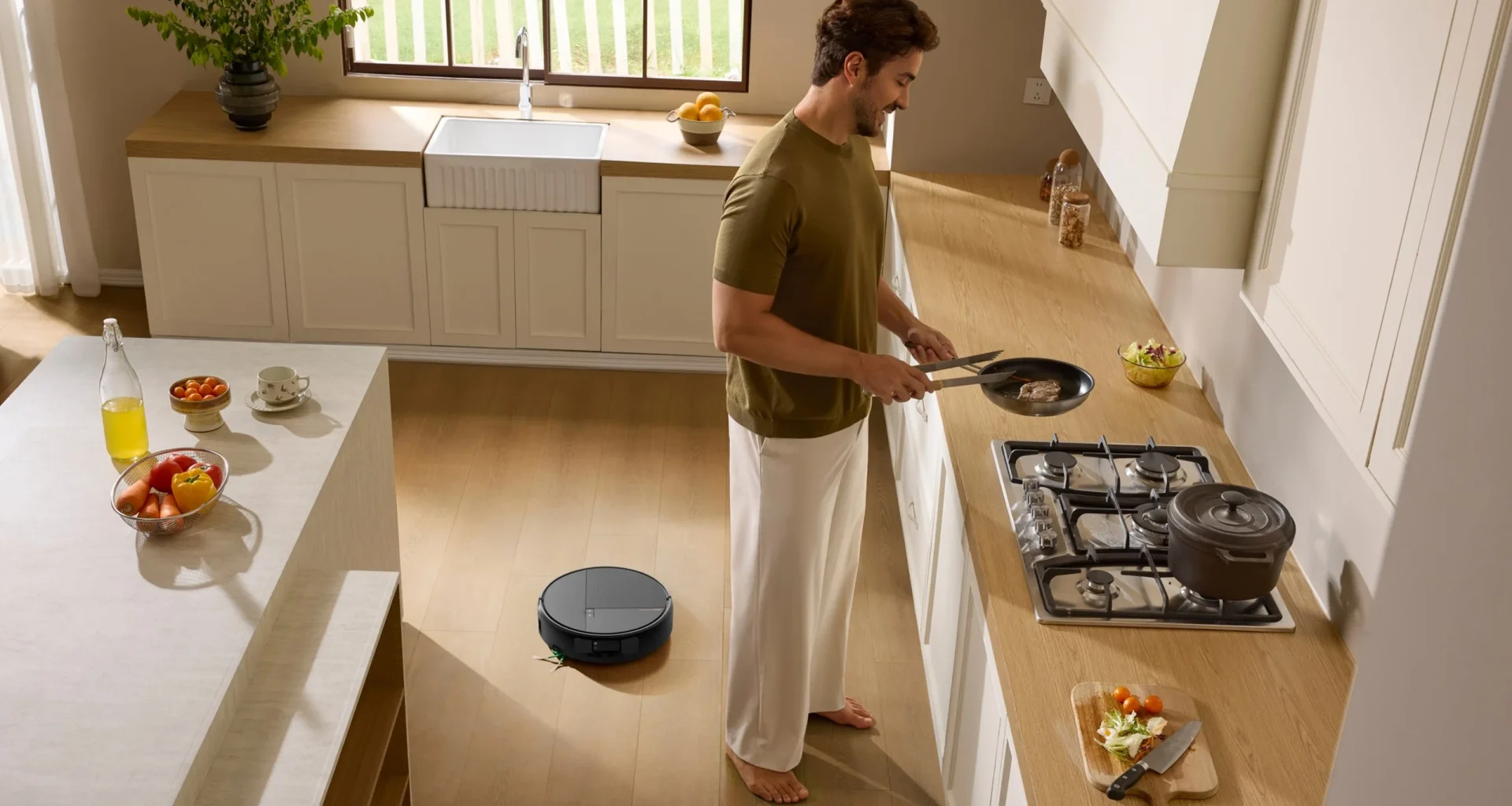 Homem a cozinhar numa cozinha moderna enquanto o aspirador robô Roomba Max 875 Combo limpa o chão de madeira
