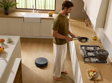 Homem a cozinhar numa cozinha moderna enquanto o aspirador robô Roomba Max 875 Combo limpa o chão de madeira