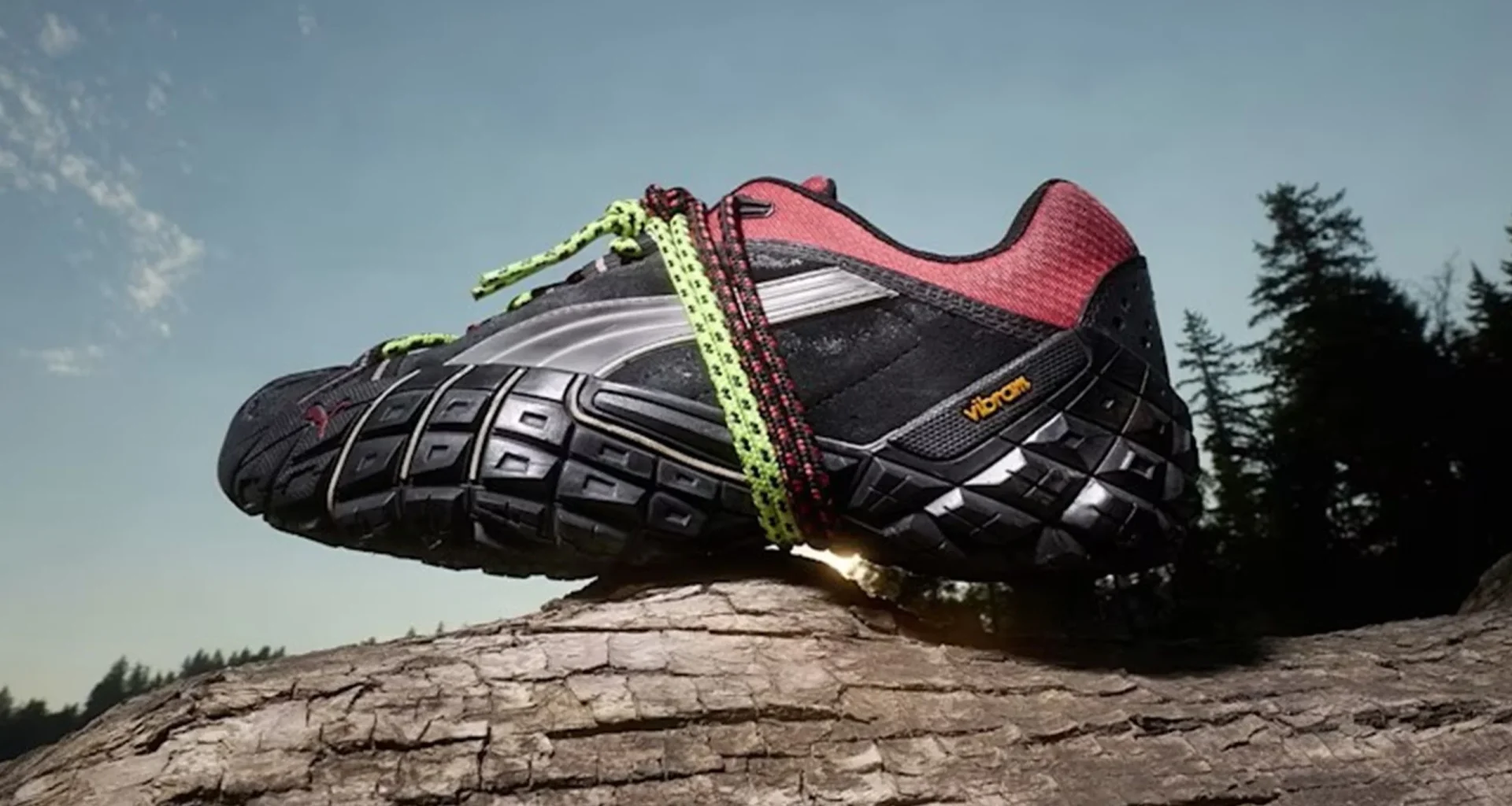 Ténis de trail Puma com sola Vibram sobre um tronco.