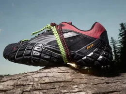 Ténis de trail Puma com sola Vibram sobre um tronco.