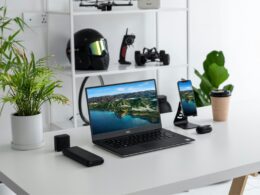 Escritório minimalista com portátil, smartphone e plantas.