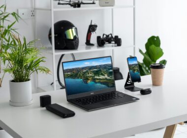 Escritório minimalista com portátil, smartphone e plantas.