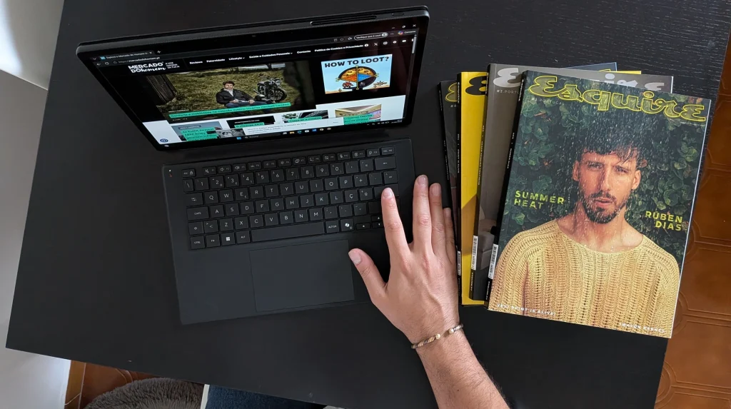 Mão sobre teclado de tablet junto a revistas Esquire.