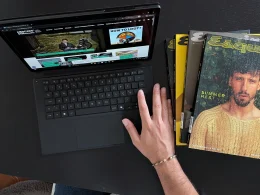 Mão sobre teclado de tablet junto a revistas Esquire.