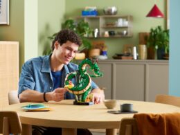 Homem sorridente a exibir modelo LEGO do dragão Shenron.