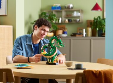 Homem sorridente a exibir modelo LEGO do dragão Shenron.
