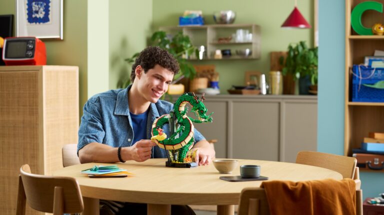 Homem sorridente a exibir modelo LEGO do dragão Shenron.