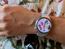 Smartwatch prateado no pulso sobre uma camisa floral.