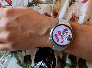 Smartwatch prateado no pulso sobre uma camisa floral.