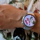 Smartwatch prateado no pulso sobre uma camisa floral.