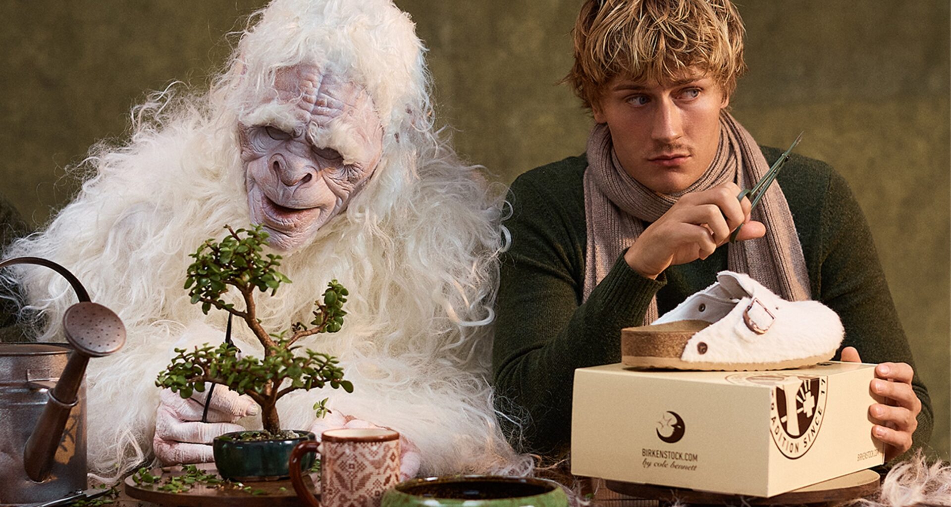 Yeti e homem com sapatos Birkenstock cuidando de um bonsai.