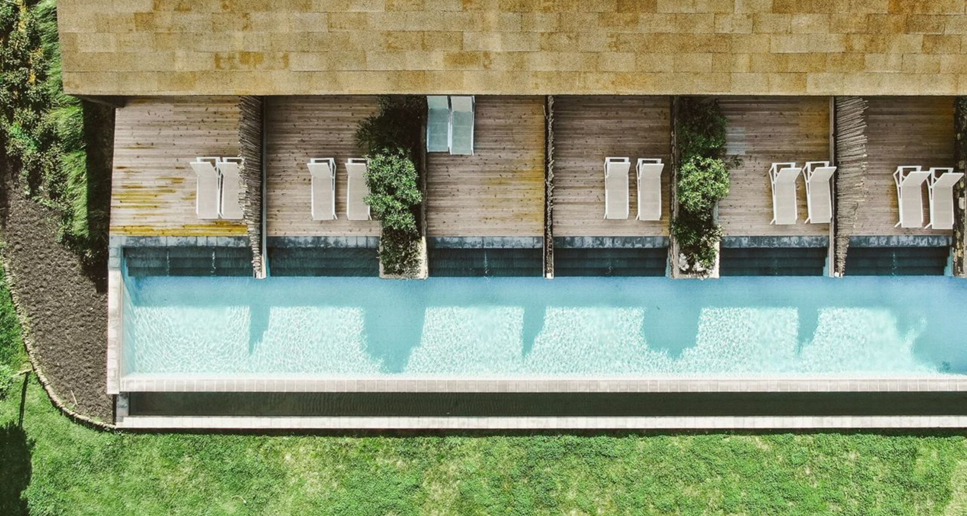 Vista aérea de piscina com espreguiçadeiras e jardim.