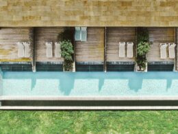 Vista aérea de piscina com espreguiçadeiras e jardim.