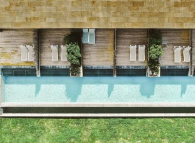 Vista aérea de piscina com espreguiçadeiras e jardim.