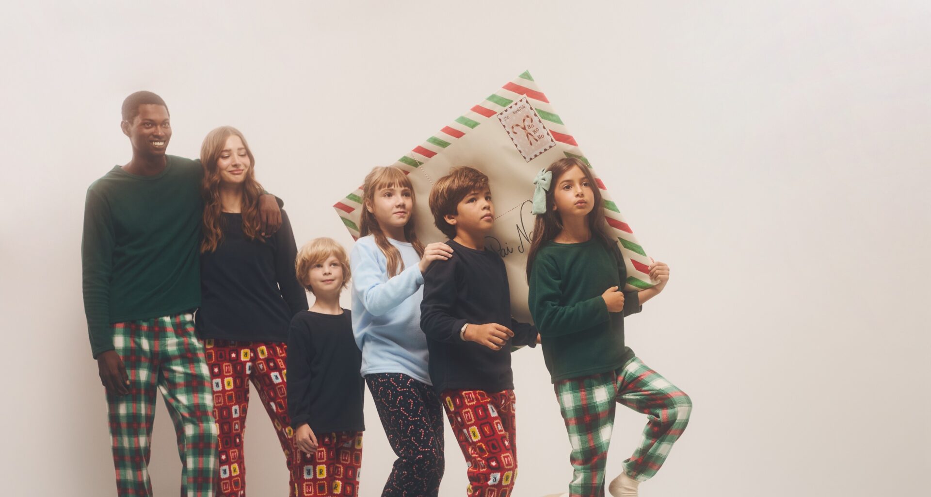 Crianças e adultos em pijamas natalícios juntos.