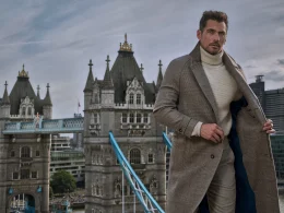 Homem elegante com sobretudo cinzento perante a Tower Bridge.