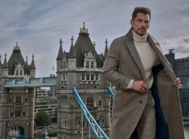 Homem elegante com sobretudo cinzento perante a Tower Bridge.