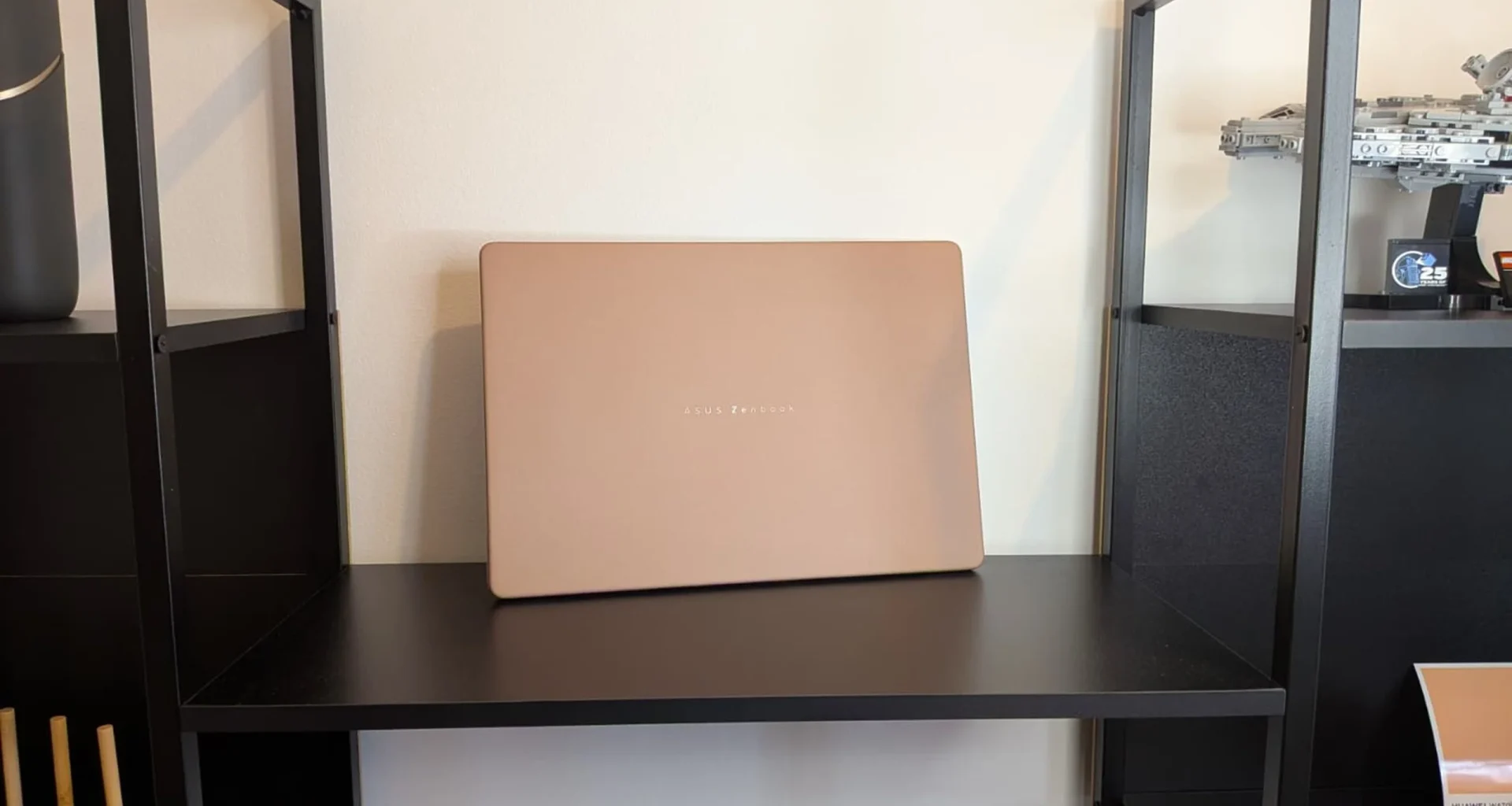 Portátil ASUS Zenbook bege pousado numa prateleira preta.