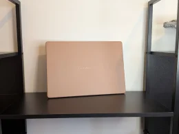 Portátil ASUS Zenbook bege pousado numa prateleira preta.