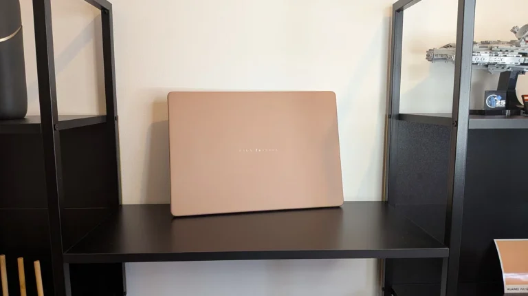 Portátil ASUS Zenbook bege pousado numa prateleira preta.