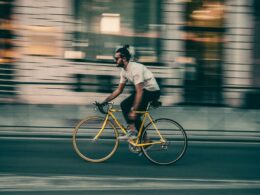 Homem a pedalar na cidade com bicicleta amarela.