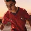 Jovem jogando futebol na praia ao pôr do sol.