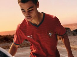 Jovem jogando futebol na praia ao pôr do sol.