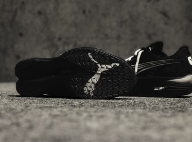 Ténis pretos em superfície de betão cinza.