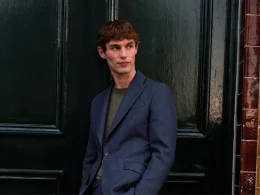 Homem elegante de fato azul junto a uma porta.