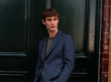 Homem elegante de fato azul junto a uma porta.