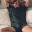 Homem em t-shirt verde e cuecas no quarto.