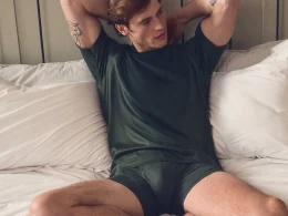 Homem em t-shirt verde e cuecas no quarto.