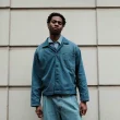 Jovem homem com roupa ganga em frente a parede com textura.
