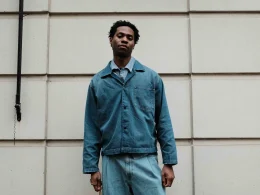 Jovem homem com roupa ganga em frente a parede com textura.