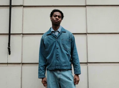 Jovem homem com roupa ganga em frente a parede com textura.