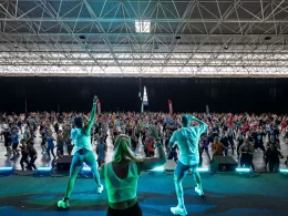 Multidão a fazer exercício em aula de fitness com instrutores.
