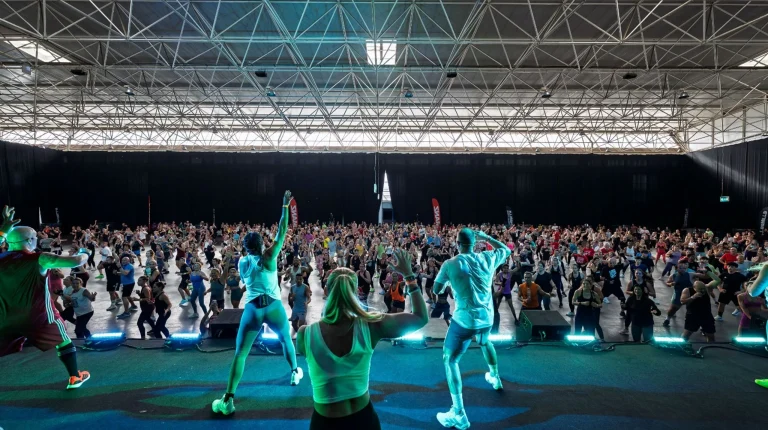 Multidão a fazer exercício em aula de fitness com instrutores.