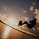 Atleta a praticar kitesurf com um salto de grande altitude ao pôr do sol nas Ilhas Canárias para ilustrar a procura constante de adrenalina