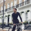 Homem a andar de bicicleta numa rua de Londres, a usar a Camisola Manga Comprida Lã Merino Decote Redondo da nova coleção IUMAN Intimissimi Uomo