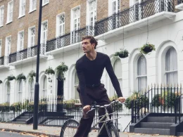 Homem a andar de bicicleta numa rua de Londres, a usar a Camisola Manga Comprida Lã Merino Decote Redondo da nova coleção IUMAN Intimissimi Uomo