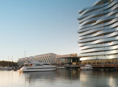 Marina com iates luxuosos e edifício moderno de vidro ondulado.