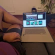 Homem a utilizar um portátil sentado confortavelmente no sofá.