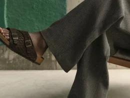 Pessoa a usar sandálias Birkenstock castanhas e calças cinzentas.